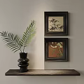 Decorative Ornament Set with Black Vase Fern Leaves and Two Framed Paintings on Wooden Table