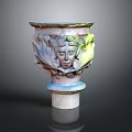 Carved Decorative Vase With Intricate Face Designs And Green Accents On Pedestal Base