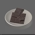 Neatly Stacked Chocolate Pieces of Different Sizes on a White Plate
