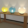 Three Colorful Spherical Table Lamps Yellow Blue White Lit on Wooden Table
