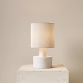 Beige Fabric Lampshade Table Lamp With White Cylindrical Base On Light Table And Beige Wall 3d model