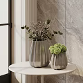 Textured Silver Vases With Green Plants And Spherical Flowers On White Round Table