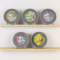 Five Circular Plates With Colorful Cartoon Patterns On Light Wooden Shelves