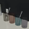 Modern Bathroom Accessories With Assorted Color Tumblers Toothbrushes And Toothpaste On White Countertop