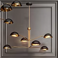 Modern Chandelier With Golden Branches And Hemispherical Black Shades Against Dark Wall