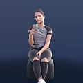 Woman Sitting On Chair Holding Smartphone Wearing Gray Top And Tight Pants