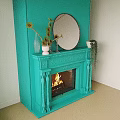 Turquoise Fireplace With Ornate Carvings Burning Flames And Potted Plants Above Mirror
