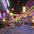 Vibrant Commercial Street With Neon Signs Storefronts Pedestrians Outdoor Seating And Lively Atmosphere