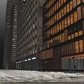 Snowy Evening Commercial Street with Tall Buildings Bright Lights and Storefronts