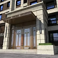 Elegant Entrance Gate With Glass Doors Stone Facade Balconies And Greenery Accents