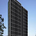 High Rise Modern Residential Building with Many Windows Trees Nearby and Blue Sky Background