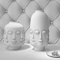 Elegant White Ceramic Vases with Face Motifs on Brown Leather Background and Black Marble Table