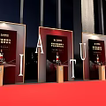 Elegant Banquet Hall Setup With Long Dining Tables Black Chairs And Red Stage Lighting