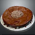 Red Round Cake With Shiny Red Glaze Topped With Crushed Nuts On White Plate