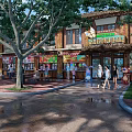 Traditional Style Commercial Street With Shops Pedestrians Trees And Rainy Atmosphere