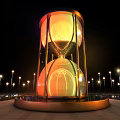 Giant Illuminated Hourglass In Night Scene With Surrounding Light Poles