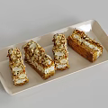 Four Layered Pastries With Almond Slices And Cream Filling On White Tray