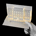 Detailed Architectural Sculpture Model With Illuminated Windows And Reflective Base Held By White Gloved Hand