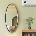Oval Metal Frame Mirror On Light Wall Near Wooden Table With Green Plant Vase