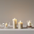 Burning Candles In Glass Holders With Various Shapes On White Shelf Background