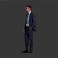 Man in Blue Suit With Glasses Standing With Hands in Pockets Against Gray Background