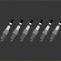 Six Spark Plugs With Silver Metal Black Tops Blue Stripes Neatly Arranged With Reflections