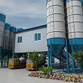 Industrial Plant with Blue and White Silos Yellow Concrete Mixers and Surrounding Flowers