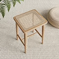 Wooden Stool with Woven Seat on Woven Mat Beside Fern Plant