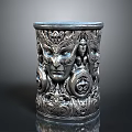 Ornate Metallic Cylindrical Container With Intricate Face Carvings And Decorative Patterns