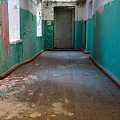 Old Elevator Corridor With Green And White Walls Peeling Paint And Debris On Wooden Floor