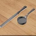 Stainless Steel Kitchen Knife and Measuring Cup with Ergonomic Handles on Wooden Tabletop