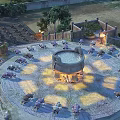 Ancient Stone Circular Structure In Central Plaza With Surrounding Seats Trees Fence And Warm Lighting