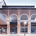 Modern Commercial Complex Featuring Red Brick Structure Arched Windows Black Roof And Plaza Area
