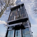 Modern High Rise Office Building with Glass Curtain Wall Surrounded by Trees Under Blue Sky