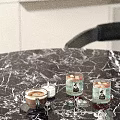 Modern Decorative Ornament Set with Coffee Cup Lit Candle and Glassware on Black Marble Tabletop