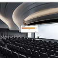 Modern Conference Room Interior With Curved Ceiling LED Lighting Rows of Seats and Lecture Stage