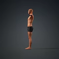 Man Standing Barefoot Shirtless in Black Shorts with Arms Outstretched Against Gray Background