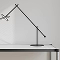 Modern Black Table Lamp With Adjustable Arm On White Desk And Light Background