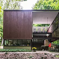 Dark Brown Wooden Detached House Surrounded by Lush Green Trees and Open Design