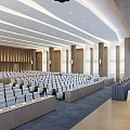Modern Conference Room With Rows Of Seats Ceiling Lights And Wooden Panel Background