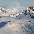 Snowy Mountain Peak With Snow Covered Slopes Rocky Outcrops Under Clear Blue Sky