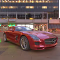 Red Mercedes Sports Car Parked On City Street With Tall Buildings And Lights