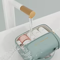 Light Green Toiletry Bag With Skincare Products As Water Splashes From Faucet
