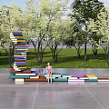 Campus Landscape Featuring Book Stacked Art Installation Lawn Trees And Colorful Seats With Students Reading