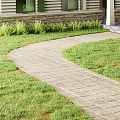 Garden Landscape Featuring Curved Brick Pathway Lush Green Lawn And House Exterior