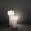 Two White Floor Lamps With Square Striped Shades And Cylindrical Stands In Dark Background