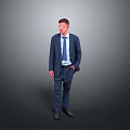 Man in Blue Suit With Glasses Standing With Hands in Pockets Against Gray Background