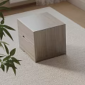 Light Wood Cube Shaped Bedside Table On Light Colored Carpet With Green Plant Leaves