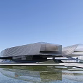 Modern Streamlined Museum Building With Glass Curtain Wall And Water Pool Reflection