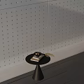 Black Side Table with Book Nuts and Hay against Gray Perforated Wall and Dark Floor